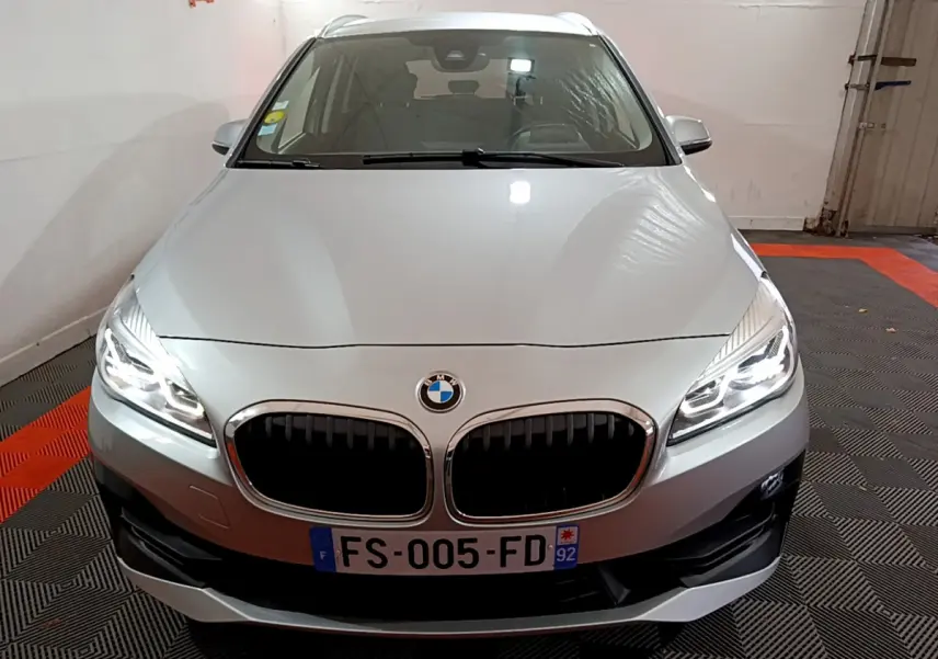 BMW Série 2 Gran Tourer gris clair vue de face avec phares LED allumés dans un garage.