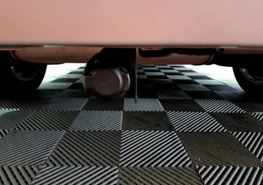 Vue en contre-plongée sous l'arrière d'une BMW Série 2 Gran Tourer gris clair, montrant la prise électrique de remorque.