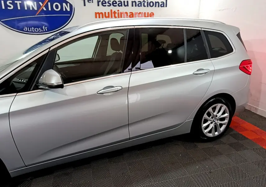 Profil côté gauche d'une BMW Série 2 Gran Tourer 218d Lounge gris clair, mettant en valeur ses vitres teintées et ses jantes alliage.