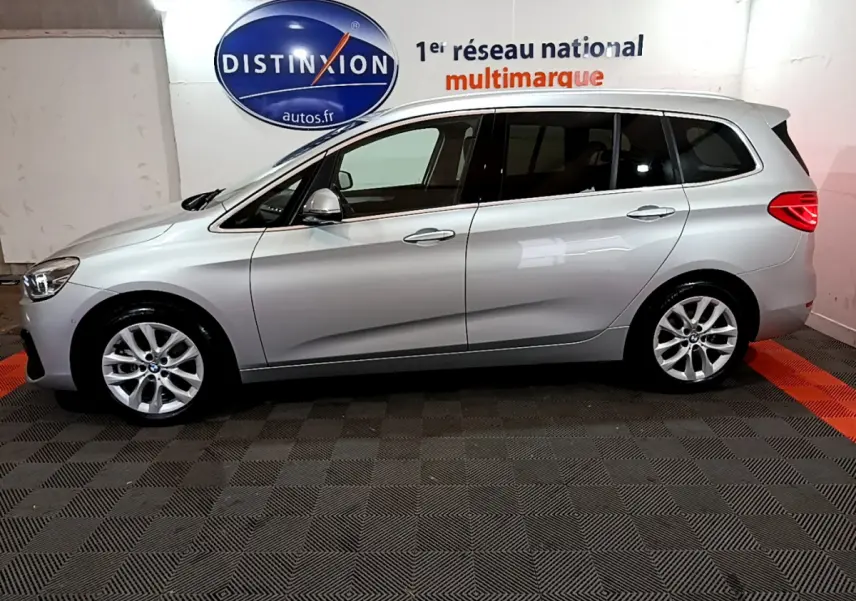 Vue de profil côté gauche d'une BMW Série 2 Gran Tourer 218d Lounge gris clair dans un showroom intérieur.