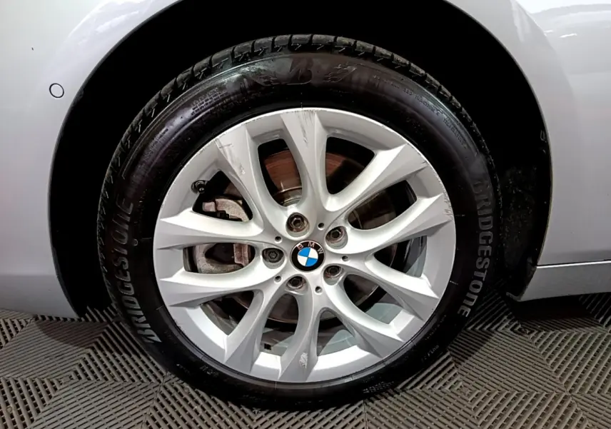 Gros plan sur la roue avant droite grise d'une BMW Série 2 Gran Tourer F46 avec jante alliage à 10 branches.