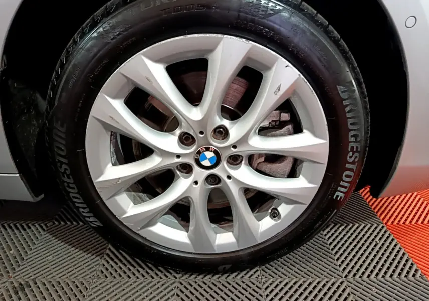 Gros plan sur la roue avant droite d'une BMW Série 2 Gran Tourer gris clair avec jante alliage et pneu Bridgestone.