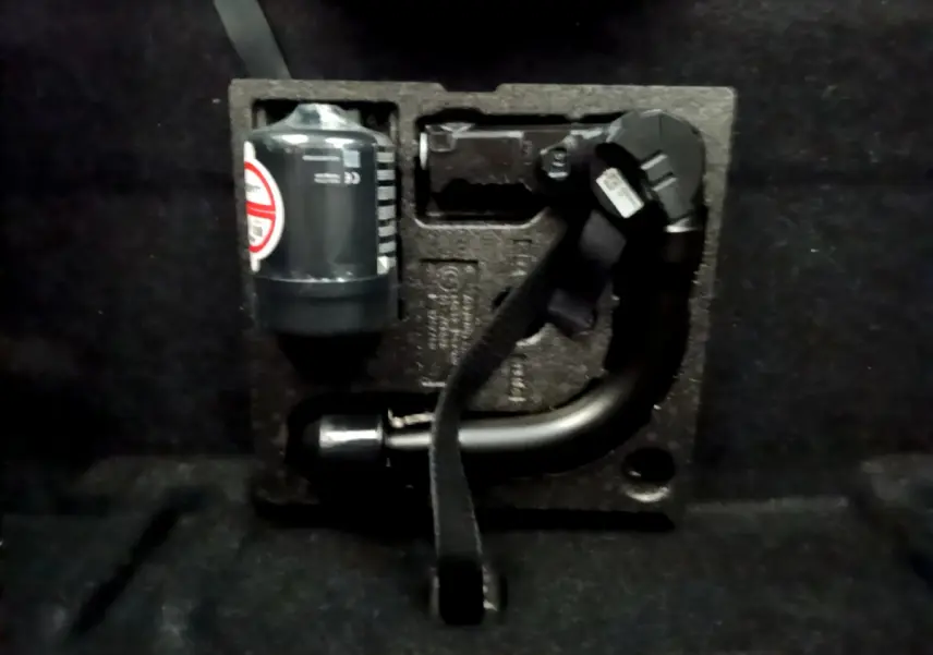 Gros plan sur le coffre d’une BMW Série 2 Gran Tourer gris clair, montrant le kit de réparation pneu intégré.