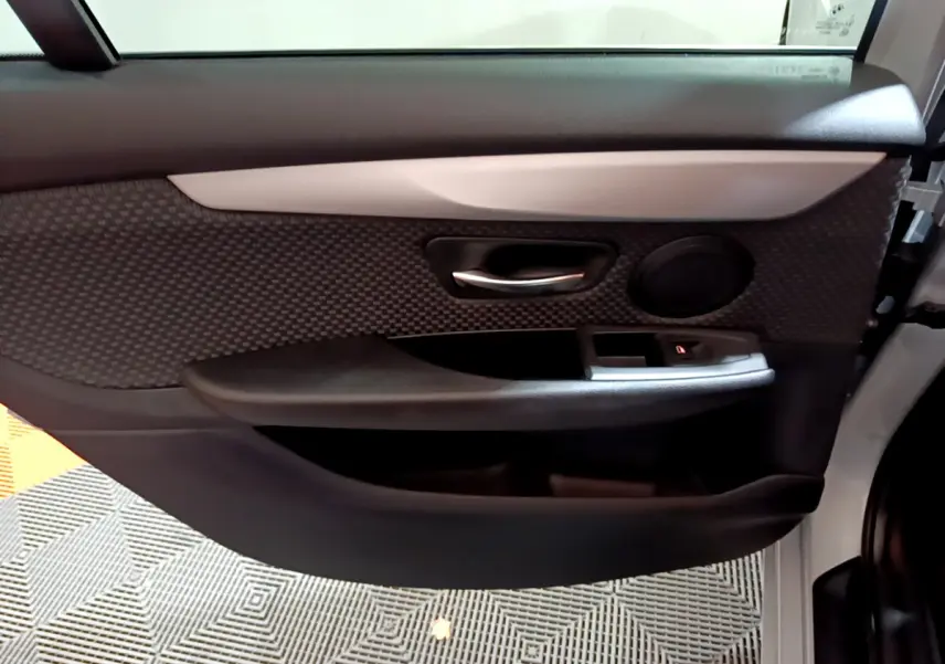 Vue rapprochée de la porte avant droite gris clair de la BMW Série 2 Gran Tourer avec garniture noire et poignée chromée.