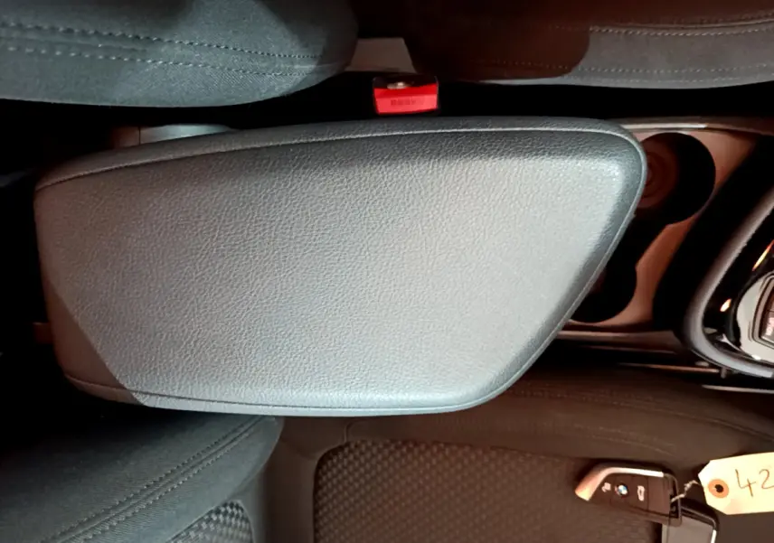 Vue rapprochée de l'accoudoir central gris clair et de la clé BMW posée sur le siège avant noir d'une Série 2 Gran Tourer F46.