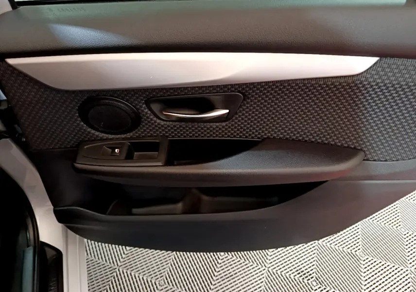 Gros plan sur la porte intérieure côté conducteur de la BMW Série 2 Gran Tourer 218d gris clair, avec habillage texturé noir.