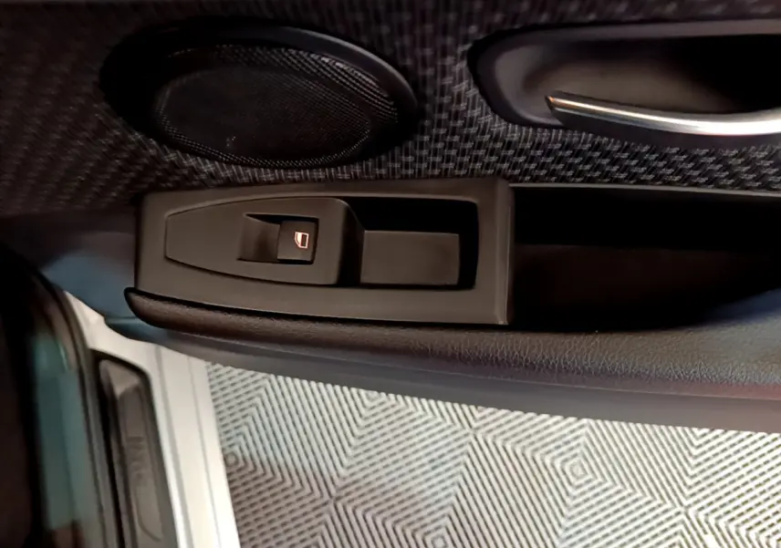 Détail de la commande de lève-vitre sur la porte côté conducteur d’une BMW Série 2 Gran Tourer gris clair.
