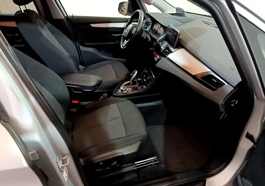 Intérieur avant droit de la BMW Série 2 Gran Tourer 218d gris clair, sièges tissu noirs et tableau de bord moderne.