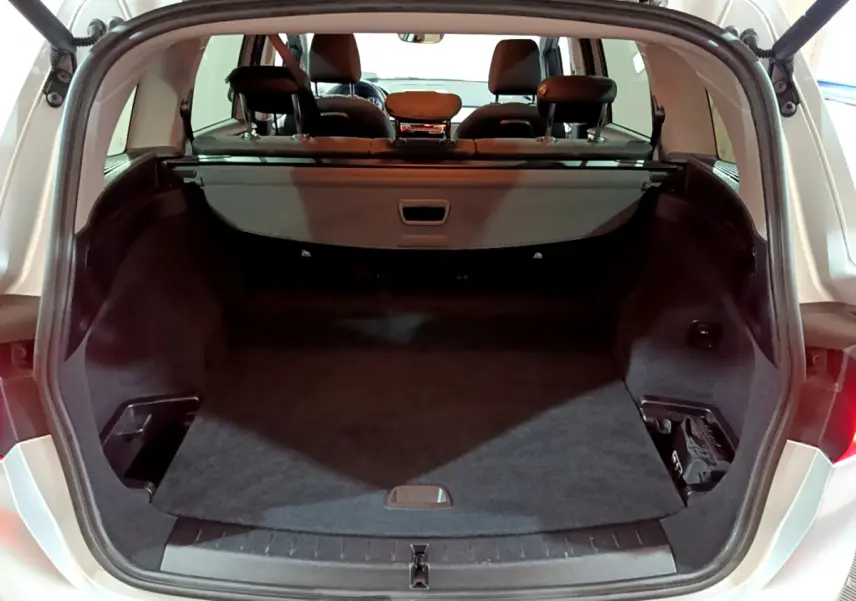 Coffre ouvert vu de l'arrière d'une BMW Série 2 Gran Tourer 218d Lounge gris clair, avec plancher plat et sièges arrière visibles.