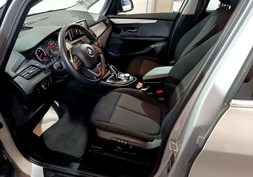 Vue intérieure côté conducteur de la BMW Série 2 Gran Tourer gris clair, avec tableau de bord et volant multifonctions en cuir.