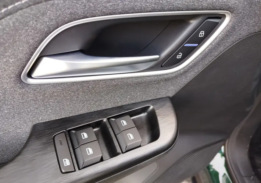 Gros plan sur la poignée intérieure et les commandes de vitres côté conducteur du MG ZS Emerald Green 2026.