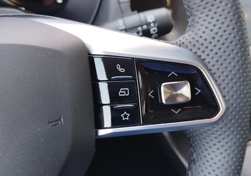 Gros plan sur les commandes multifonctions à droite du volant perforé du MG MOTOR ZS Emerald Green Hybrid 2026.