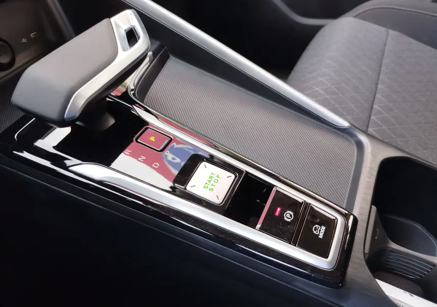 Gros plan sur la console centrale noire brillante du MG ZS 1.5L Hybrid+ 2026, montrant levier de vitesses et boutons start/stop.