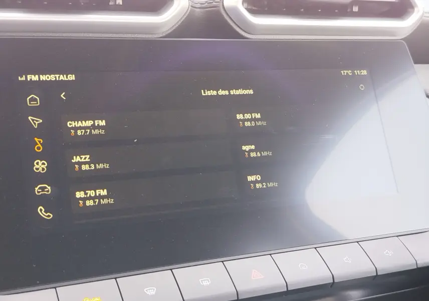 Écran tactile central du MG ZS 2026 affichant la liste des stations radio, avec commandes climatisation en bas.