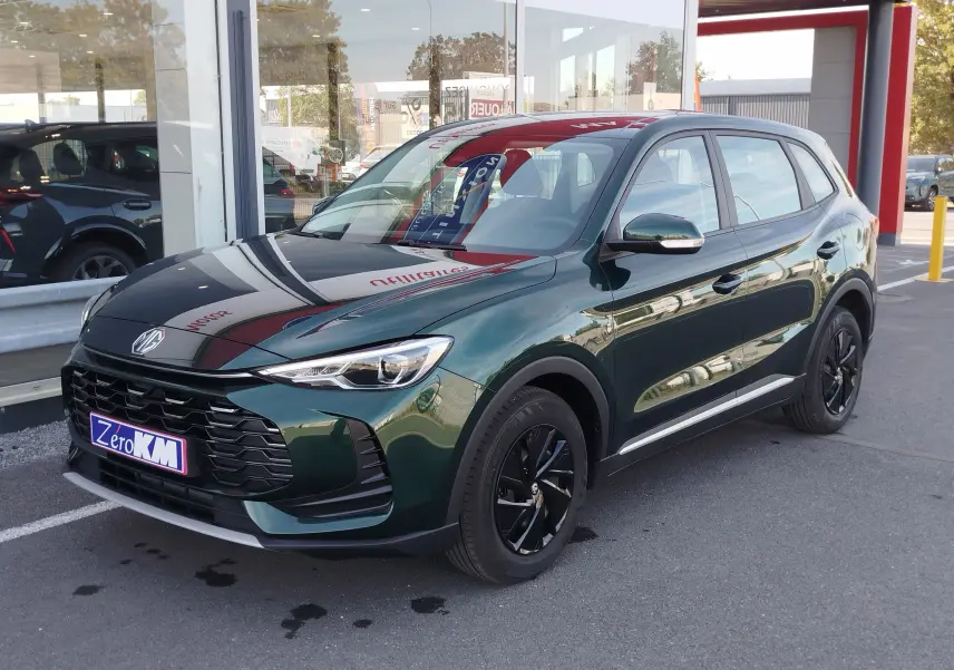 Vue 3/4 avant droit d’un MG ZS 1.5L Hybrid+ 197ch en vert émeraude métallisé avec jantes noires et calandre imposante.