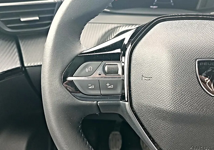 Gros plan sur la partie gauche du volant multifonction noir du Peugeot 2008 avec commandes audio intégrées.