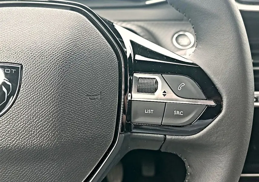 Gros plan sur le volant multifonction noir de la Peugeot 2008 2025 avec commandes audio et téléphone intégrées.