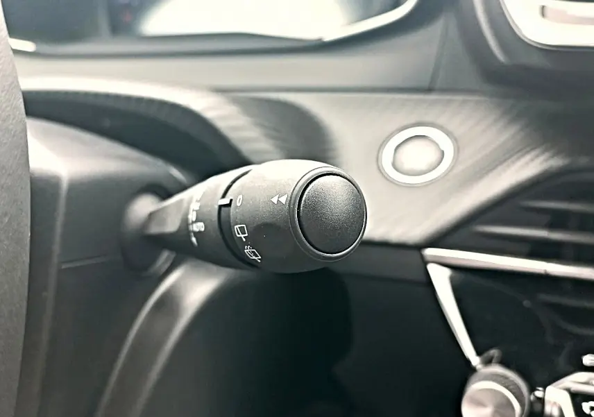 Gros plan sur la commande d’essuie-glace côté gauche du tableau de bord noir du Peugeot 2008 rouge Elixir.