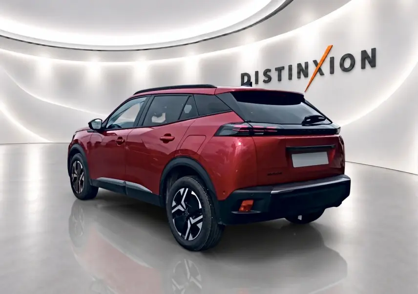Peugeot 2008 rouge elixir vue 3/4 arrière droit dans un showroom lumineux avec jantes alu et toit noir.