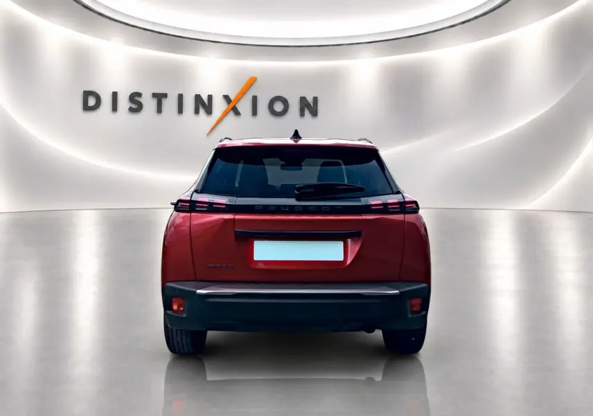 Vue arrière d'un Peugeot 2008 rouge elixir dans un showroom avec éclairage moderne et logo Distinxion.