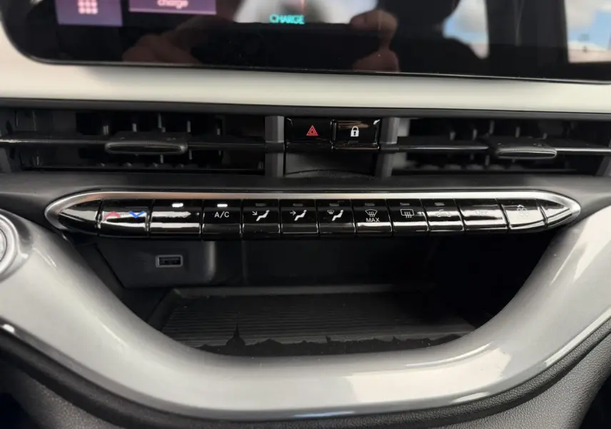 Vue rapprochée de la console centrale de la Fiat 500 électrique blanche, montrant les commandes de climatisation et un port USB.
