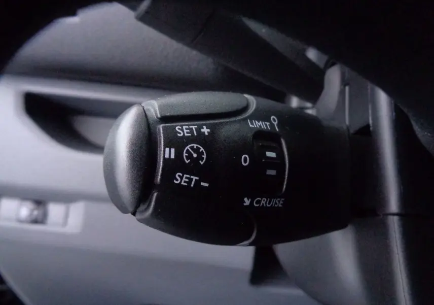 Gros plan sur la commande de régulateur de vitesse du Peugeot Expert Fourgon noir métal, version 2022, intérieur sombre.