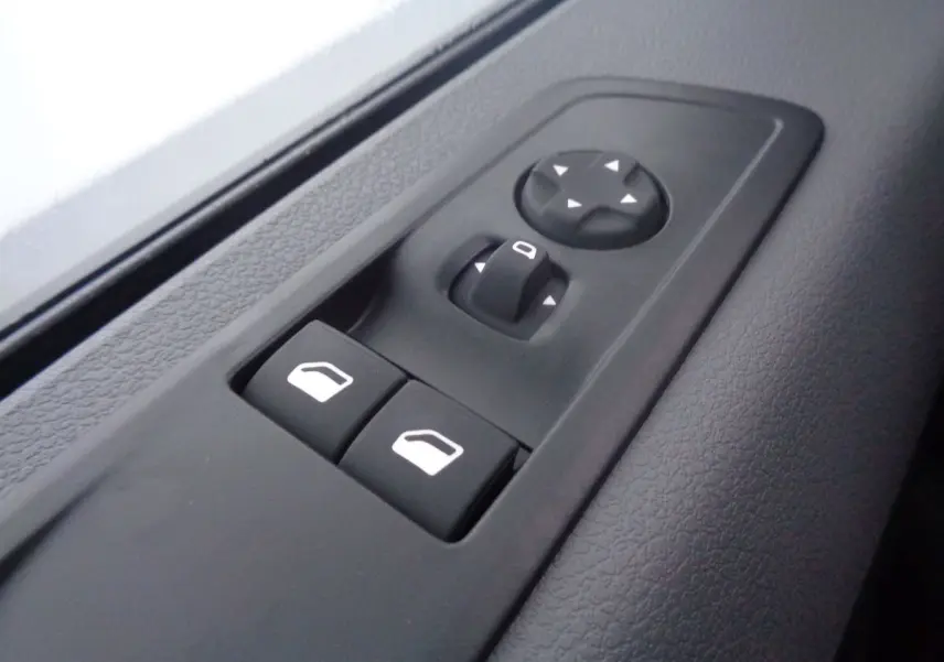 Gros plan sur les commandes de réglage des rétroviseurs et des vitres électriques côté conducteur du Peugeot Expert Fourgon noir métal 2022.