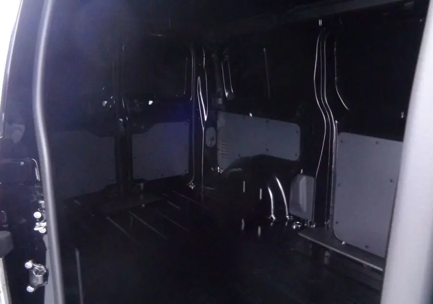 Intérieur du fourgon Peugeot Expert Standard noir métal 2022, vue depuis la porte latérale ouverte montrant l'espace de chargement vide.
