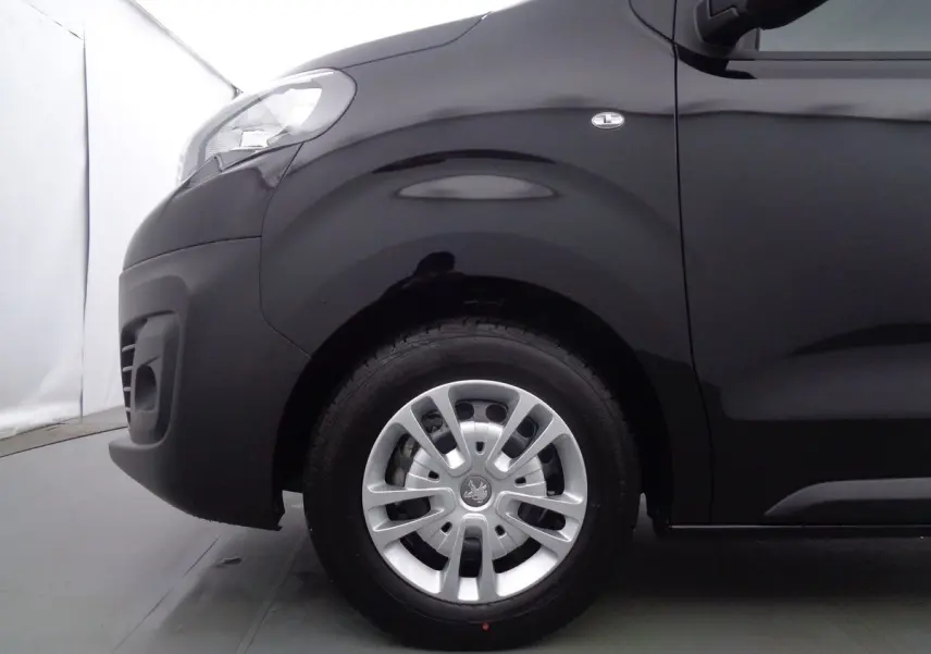 Gros plan sur la roue avant gauche d'un Peugeot Expert Fourgon noir métal 2022, avec jante argentée et logo Peugeot visible.
