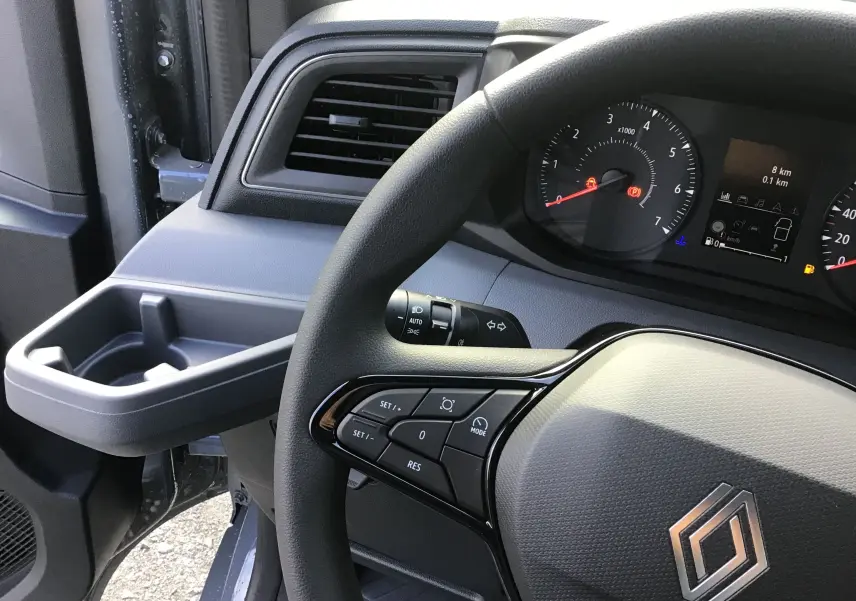 Vue intérieure rapprochée du volant et tableau de bord du Renault Master 2025, avec commandes au volant visibles.