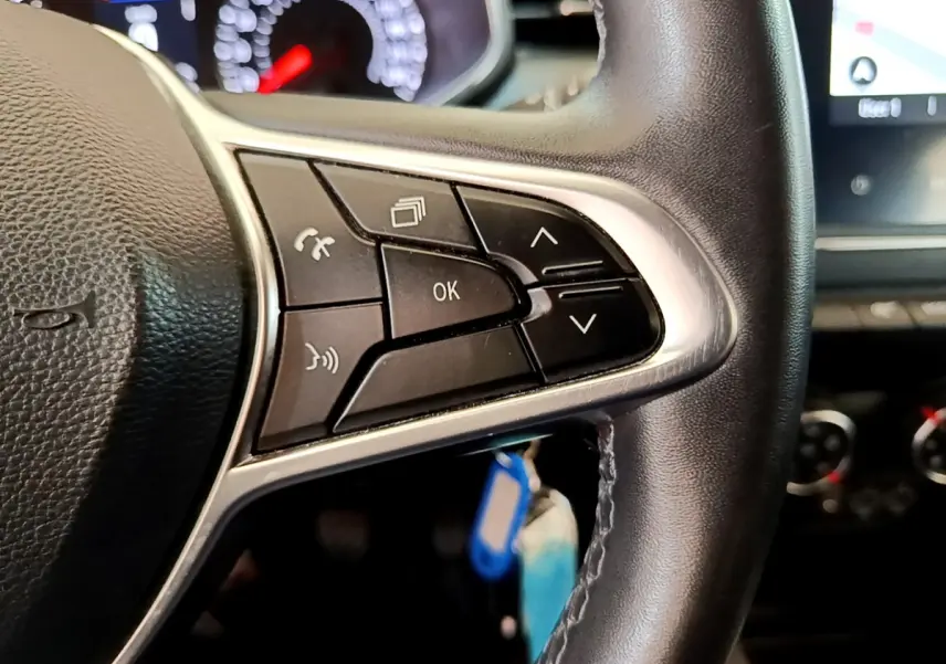 Gros plan sur les commandes multifonctions noires du volant en cuir synthétique de la Renault Clio Business Blue dCi 85, intérieur noir.