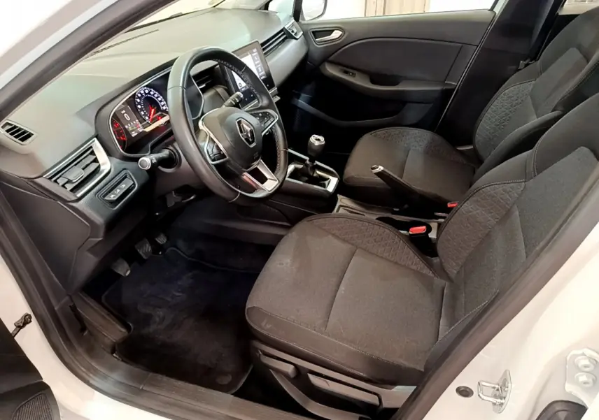 Vue intérieure côté conducteur de la Renault Clio Business Blue dCi 85 blanche, avec tableau de bord et volant multifonctions en cuir.