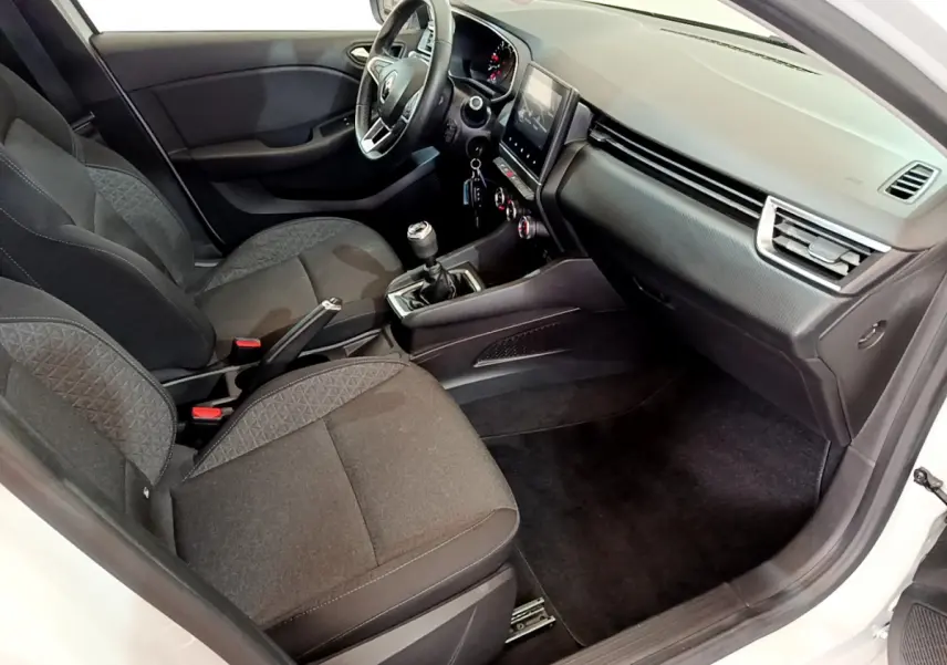 Vue intérieure côté passager de la Renault Clio Business Blue dCi 85 blanche, montrant sièges noirs et tableau de bord moderne.