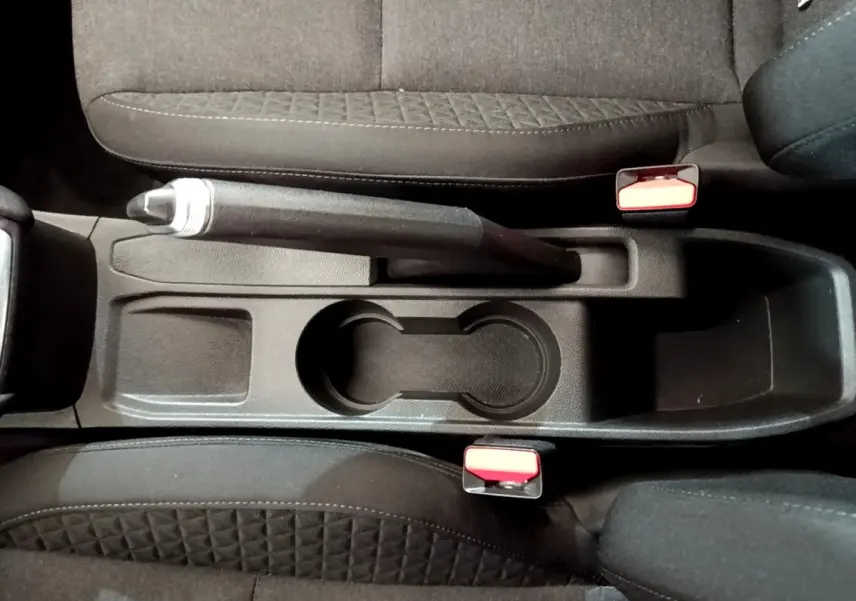 Vue plongeante sur la console centrale noire de la Renault Clio Business Blue dCi 85 avec frein à main et porte-gobelets.