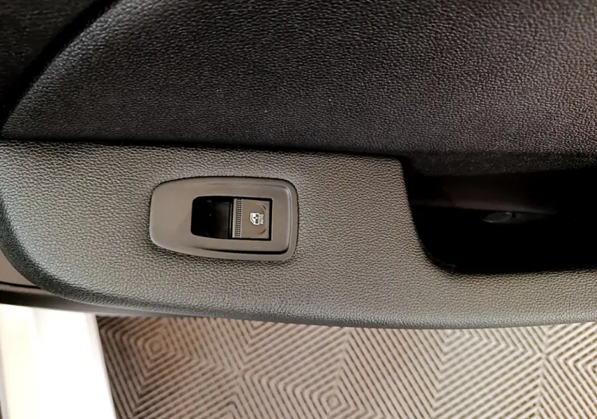 Gros plan sur le bouton de commande de la vitre électrique côté conducteur d'une Renault Clio blanche de 2020.