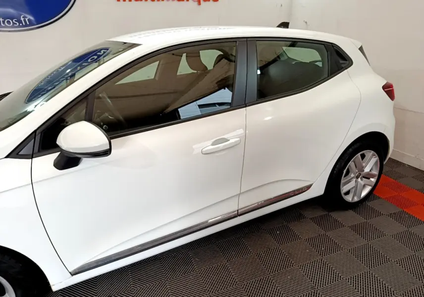 Profil côté gauche d'une Renault Clio Business Blue dCi 85 blanche, avec jantes alliage et logo Clio sur la bas de porte.