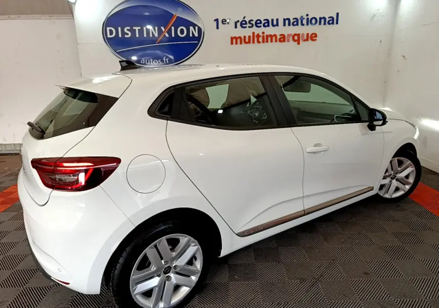 Renault Clio Business Blue dCi 85 blanc vue de profil côté droit en intérieur avec logo Distinxion en arrière-plan.