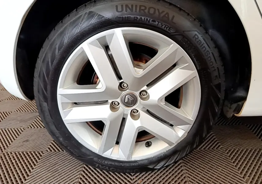 Gros plan sur la roue avant droite d'une Renault Clio blanche, avec jante alliage et pneu Uniroyal RainSport 5.