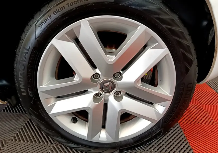 Gros plan sur la jante argentée d'une Renault Clio blanche, mettant en valeur le logo central et le pneu UniRoyal.