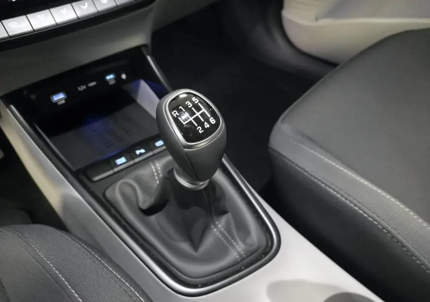 Le levier de vitesses manuel noir du Hyundai BAYON 2025 vu en gros plan côté conducteur avec console grise et sièges foncés.