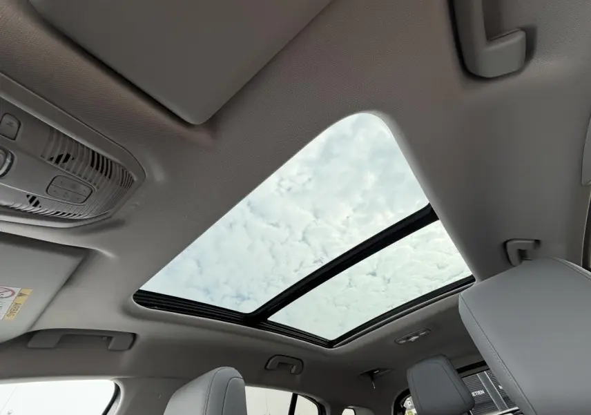 Vue intérieure du toit ouvrant panoramique vitré du Citroën C5 Aircross gris métal avec sièges avant clairs visibles.