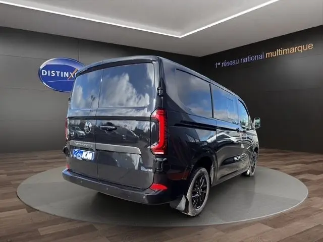Vue 3/4 arrière droite d’un Volkswagen Transporter noir brillant, avec feux arrière LED et jantes noires.