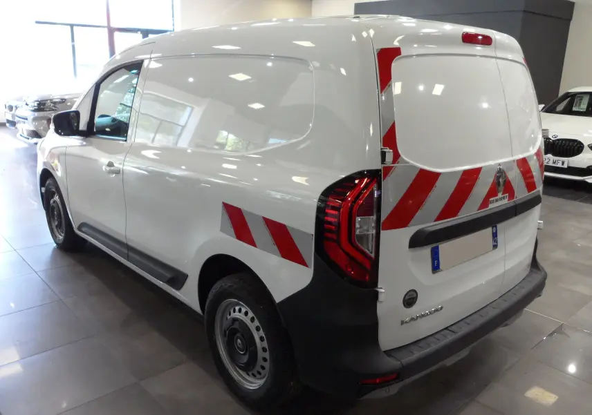 Vue 3/4 arrière droite d'un Renault Kangoo Van blanc minéral avec bandes réfléchissantes rouges et blanches sur la porte arrière et l'aile.