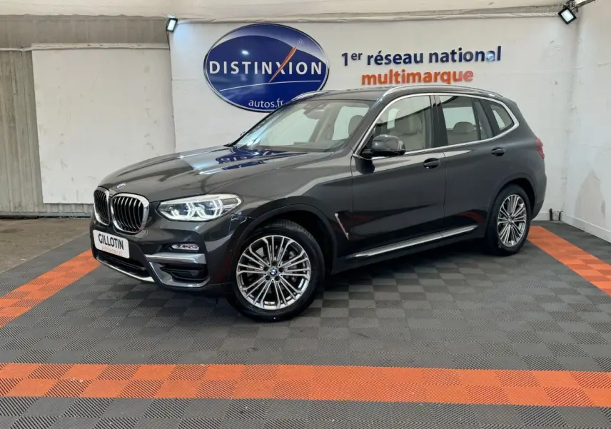BMW X3 xDrive30d gris foncé vu de 3/4 avant droit dans un showroom avec sol noir et orange.