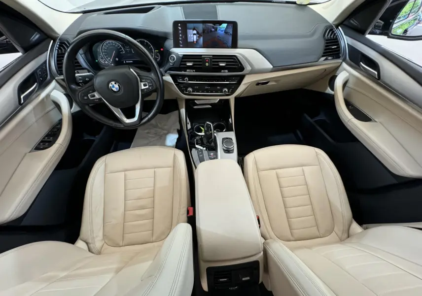 Intérieur beige clair de BMW X3 xDrive30d 2018 vu de dessus, avec tableau de bord moderne et écran tactile central.
