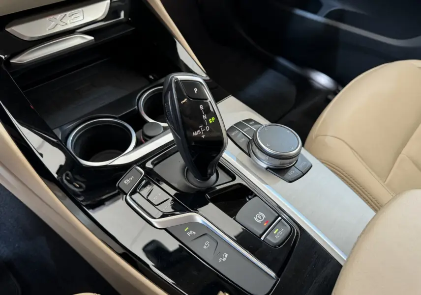 Gros plan sur la console centrale beige du BMW X3 xDrive30d 2018 avec levier de vitesses automatique et molette de commande.