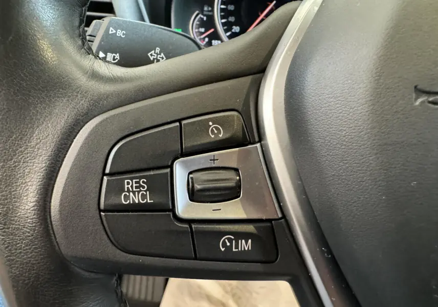 Gros plan sur les commandes du régulateur de vitesse au volant cuir du BMW X3 gris foncé, version Luxury 2018.