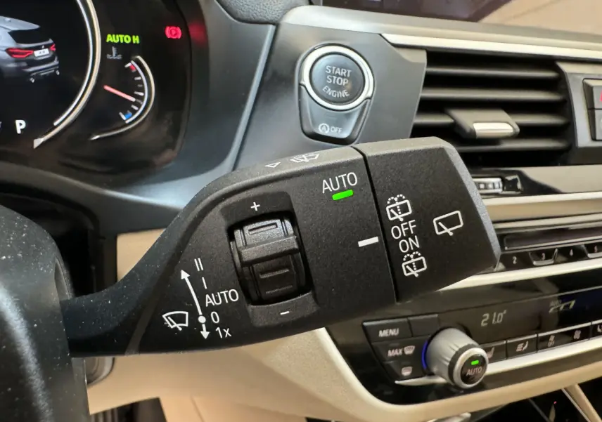 Gros plan sur la commande d’essuie-glace avec bouton start-stop, tableau de bord beige et noir d’un BMW X3 gris foncé.