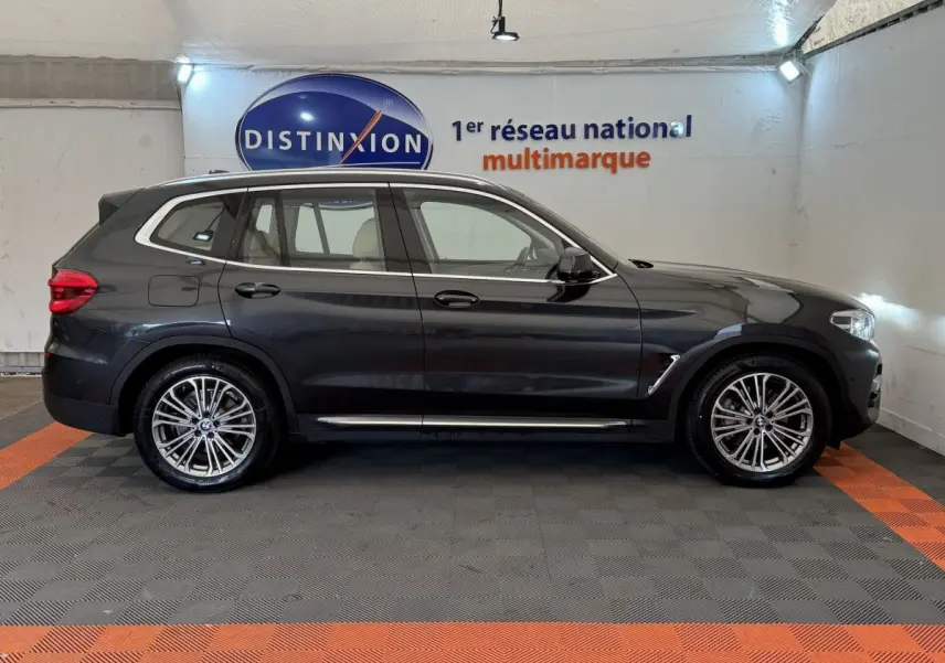 BMW X3 xDrive30d gris foncé vu de profil côté gauche, avec jantes alliage et toit noir dans un showroom.