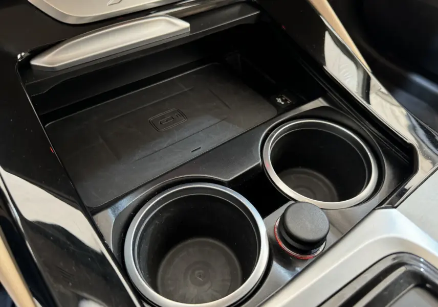Gros plan sur la console centrale noire du BMW X3 2018 avec porte-gobelets et zone de recharge sans fil.